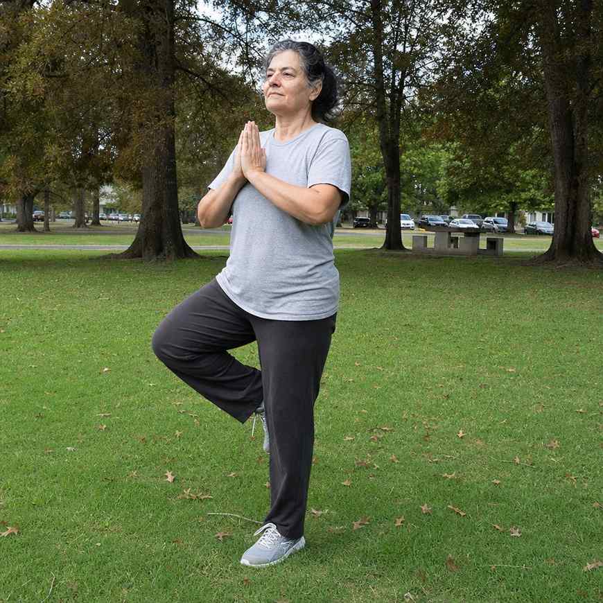 A standing balance pose on a park lawn